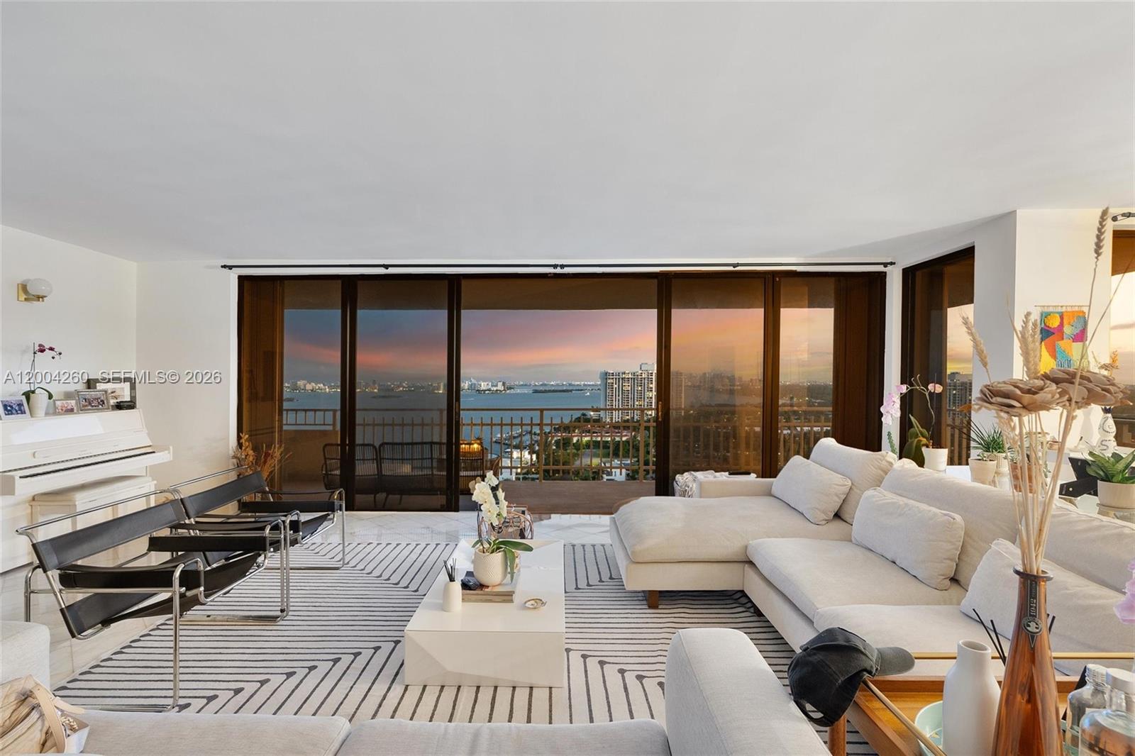 A living room features a white sectional sofa, black leather chairs, and floor-to-ceiling balcony doors — 11113 Biscayne Blvd # 2051, Miami FL 33181, MIAMI, FL