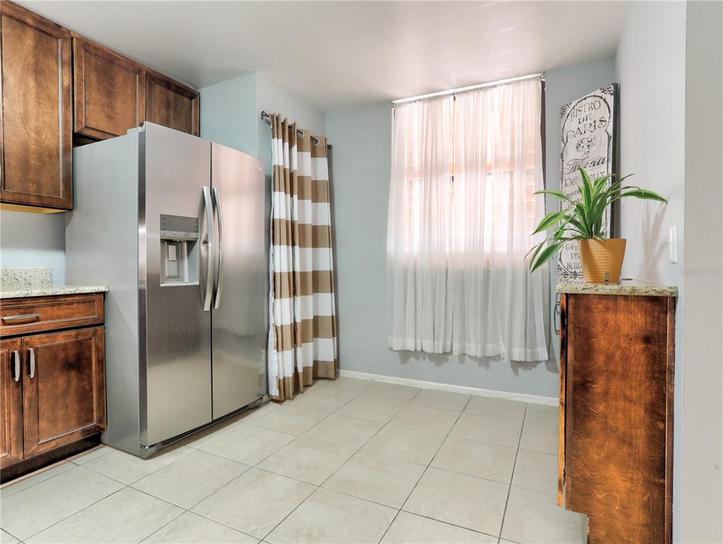 A kitchen features dark wood cabinets, a stainless steel refrigerator, and a window with curtains — 133 WILD PALM DRIVE UNIT 133, BRADENTON, FL