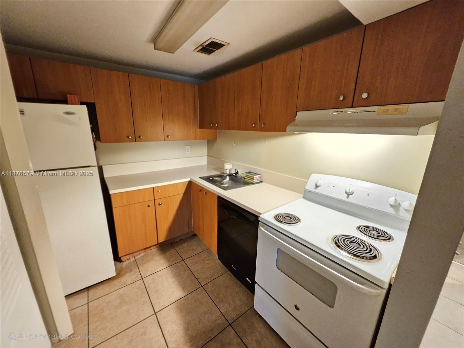 A kitchen features wood cabinets, white appliances, a black dishwasher, and light-colored tile flooring — 411 Executive Center Dr # 209, West Palm Beach FL 33401, WEST PALM BEACH, FL