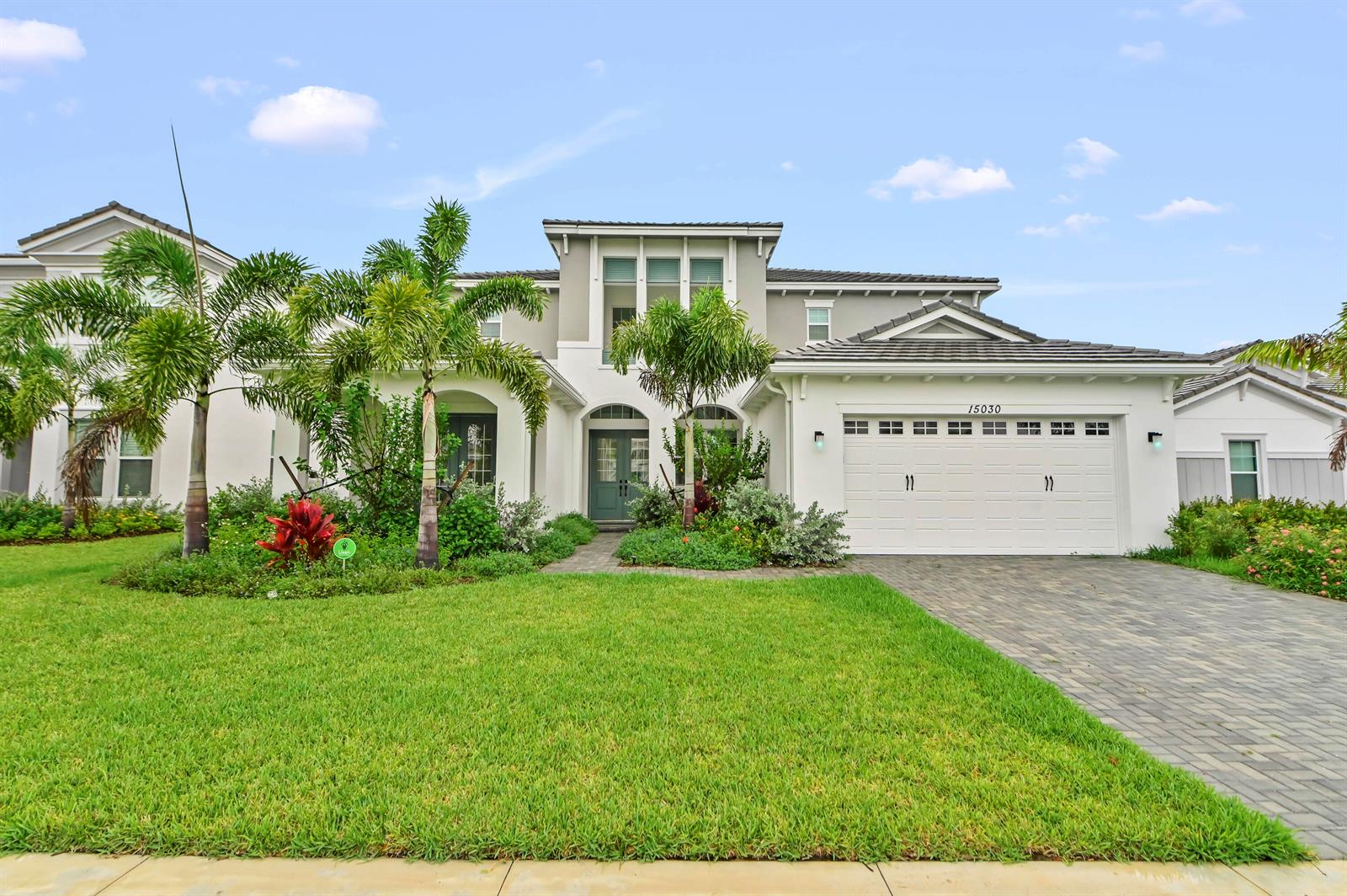 A two-story house with a white exterior, a paved driveway, and palm trees in front — 15030 Wildwood Circle, Westlake FL 33470, WESTLAKE, FL