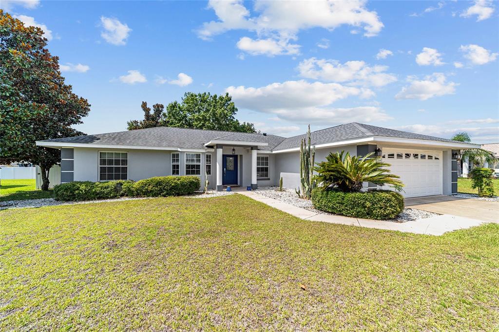 A single-story house with a gray exterior, blue front door, and a two-car garage — 6880 SE 103RD PLACE, BELLEVIEW, FL