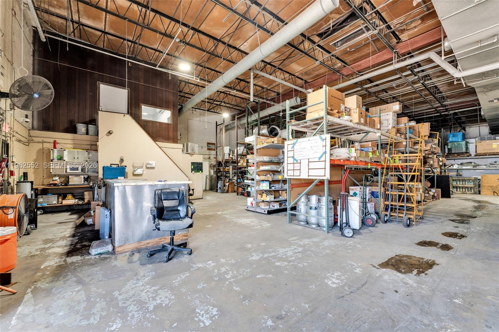 A warehouse interior features high ceilings, exposed ductwork, metal shelving units, and a service counter — 215 W 75th Pl Unit A, Hialeah FL 33014, HIALEAH, FL