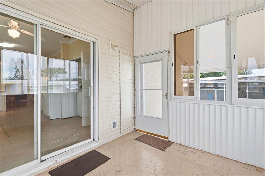 A covered patio with a sliding glass door, a screen door, and light-colored siding — 9790 66TH STREET N UNIT 357, PINELLAS PARK, FL