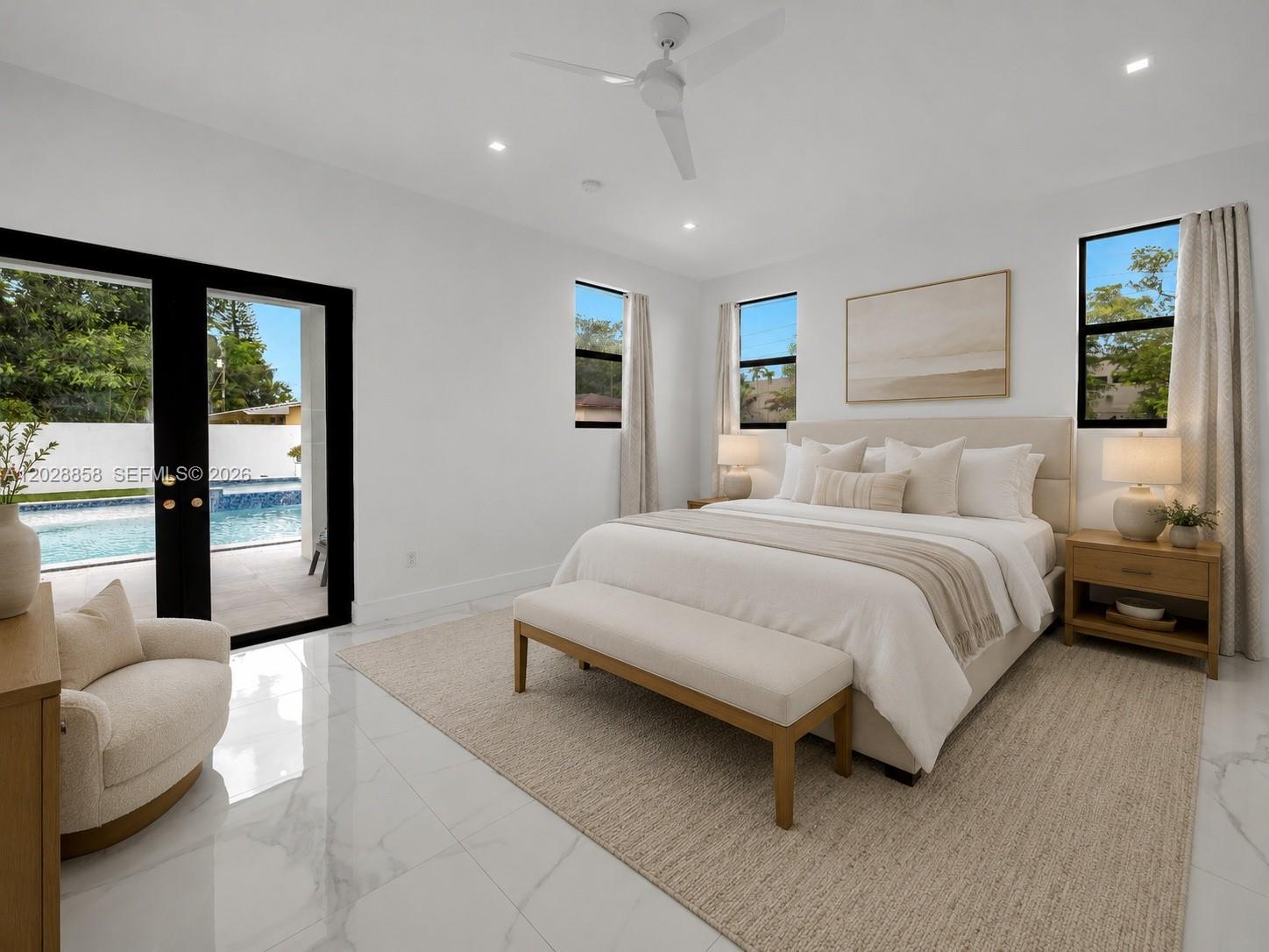 A bright bedroom features white marble floors, a king bed, and sliding doors to a pool — 152 NW 165th St, Miami FL 33169, MIAMI, FL