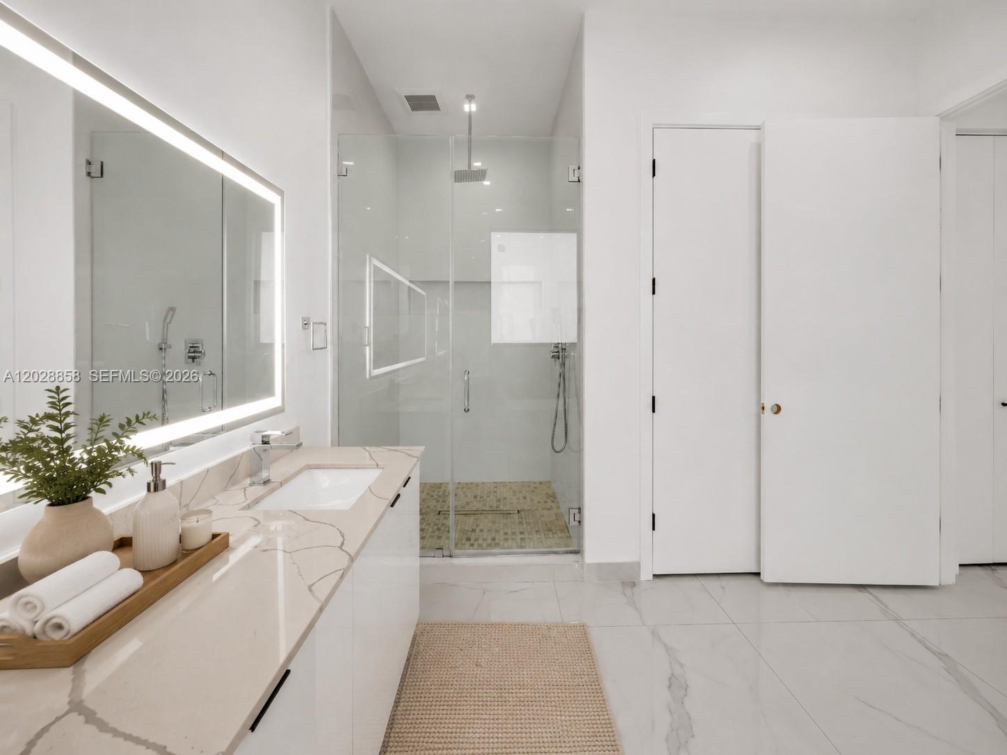 A modern bathroom features a white vanity with marble countertop, glass shower, and tiled floors — 152 NW 165th St, Miami FL 33169, MIAMI, FL
