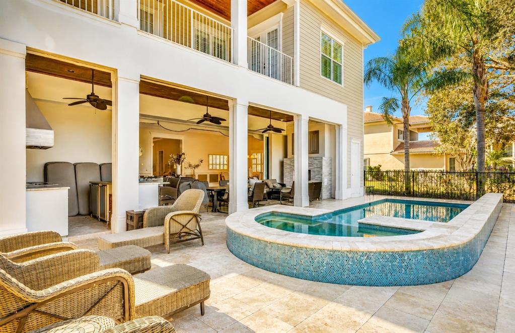 A covered patio with an outdoor kitchen overlooks a swimming pool and spa — 7453 GATHERING DRIVE, REUNION, FL
