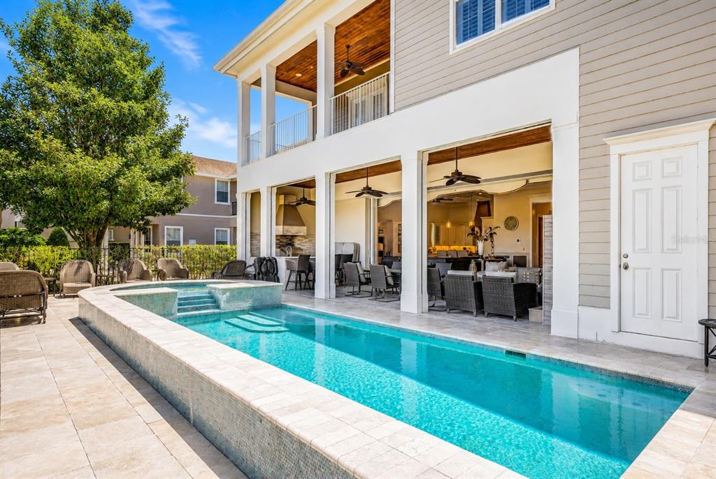 A rectangular swimming pool sits on a stone patio beside a two-story house with porches — 7453 GATHERING DRIVE, REUNION, FL