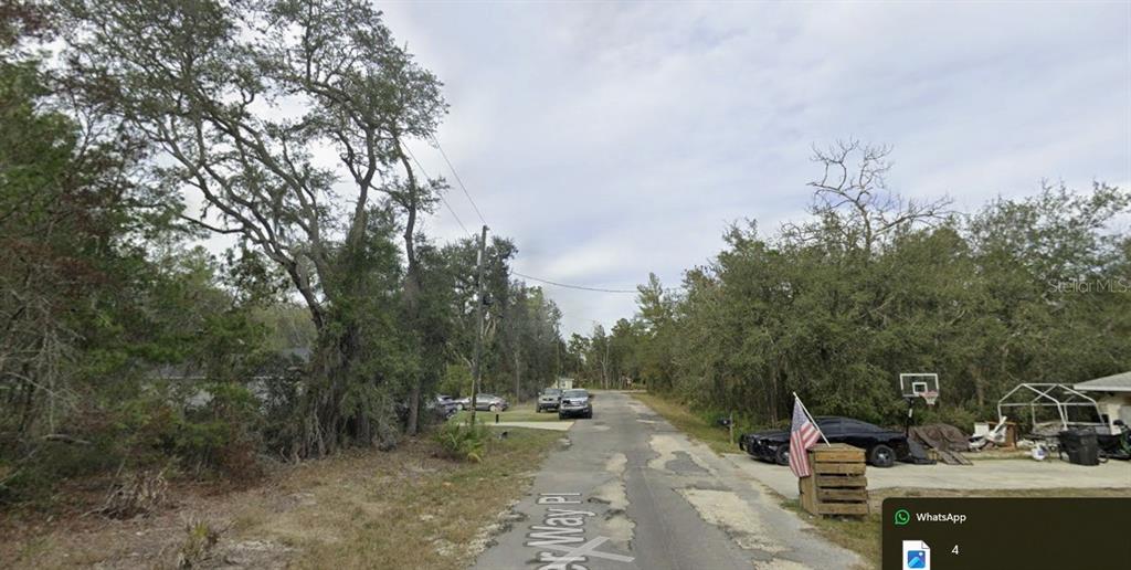 A paved street lined with trees and residential properties under a cloudy sky — TBD SE FISHER WAY PL, OCKLAWAHA, FL