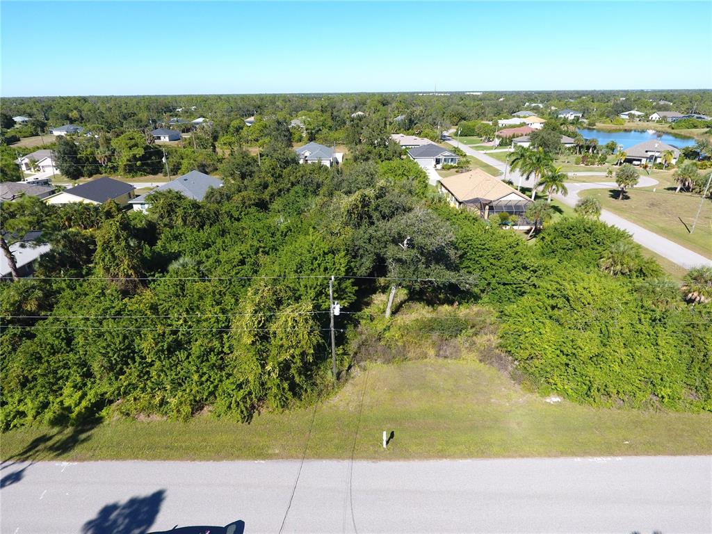 An aerial view shows a vacant, wooded residential lot situated between two existing houses — 394 ALBATROSS ROAD, ROTONDA WEST, FL