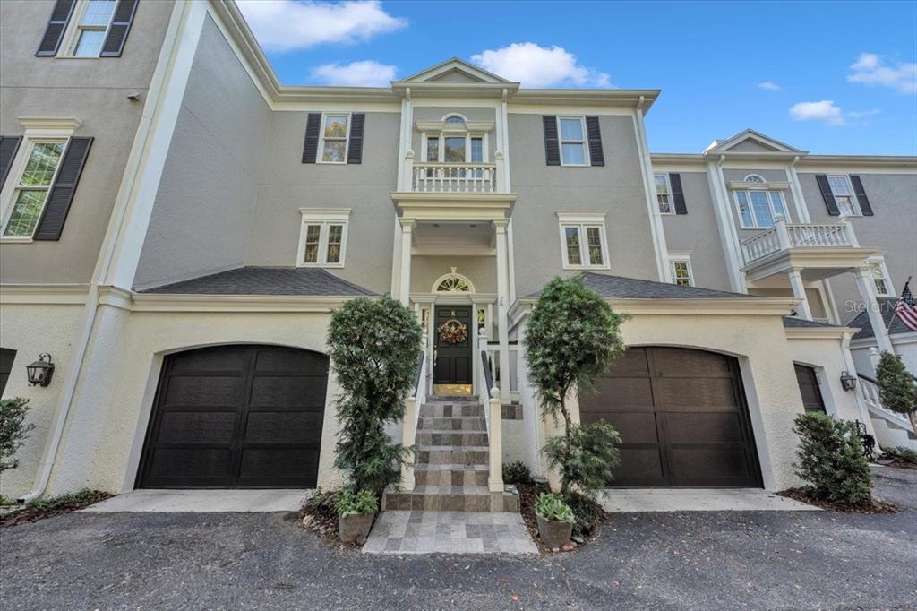 A three-story townhouse exterior features two dark garage doors, a central staircase, and a balcony — 6212 BAYSHORE BOULEVARD UNIT K, TAMPA, FL