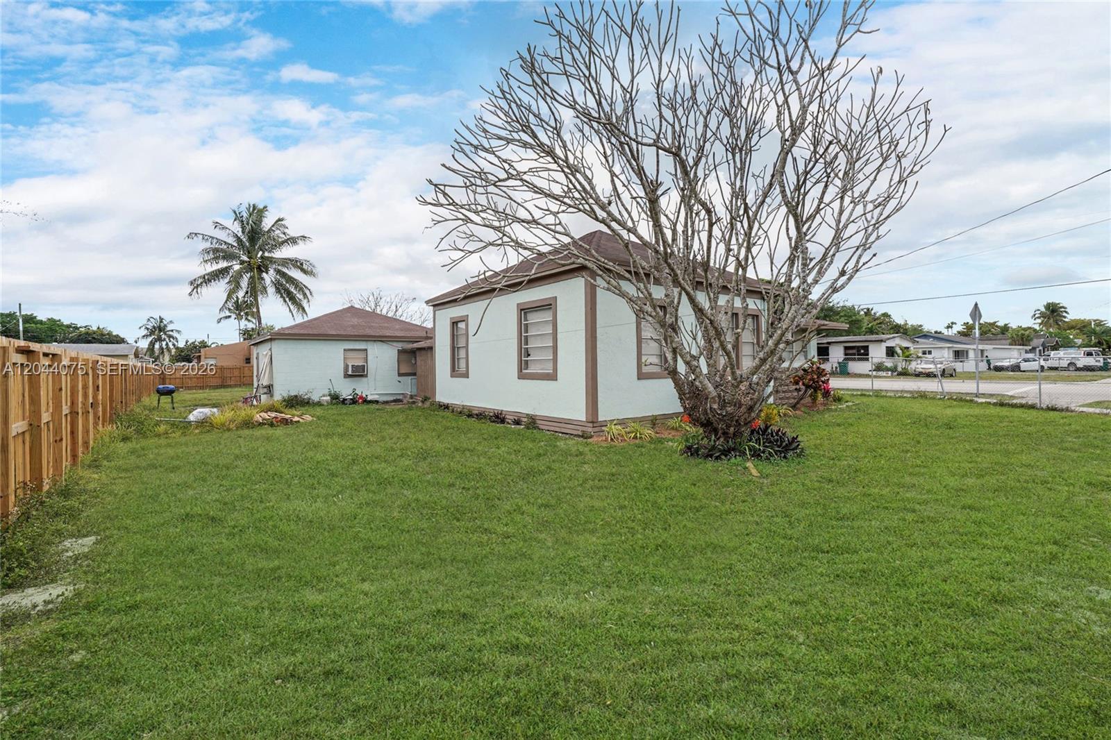 A light-colored house with brown trim sits on a grassy lot with a large tree — 145 NW 6th Ave, Florida City FL 33034, FLORIDA CITY, FL