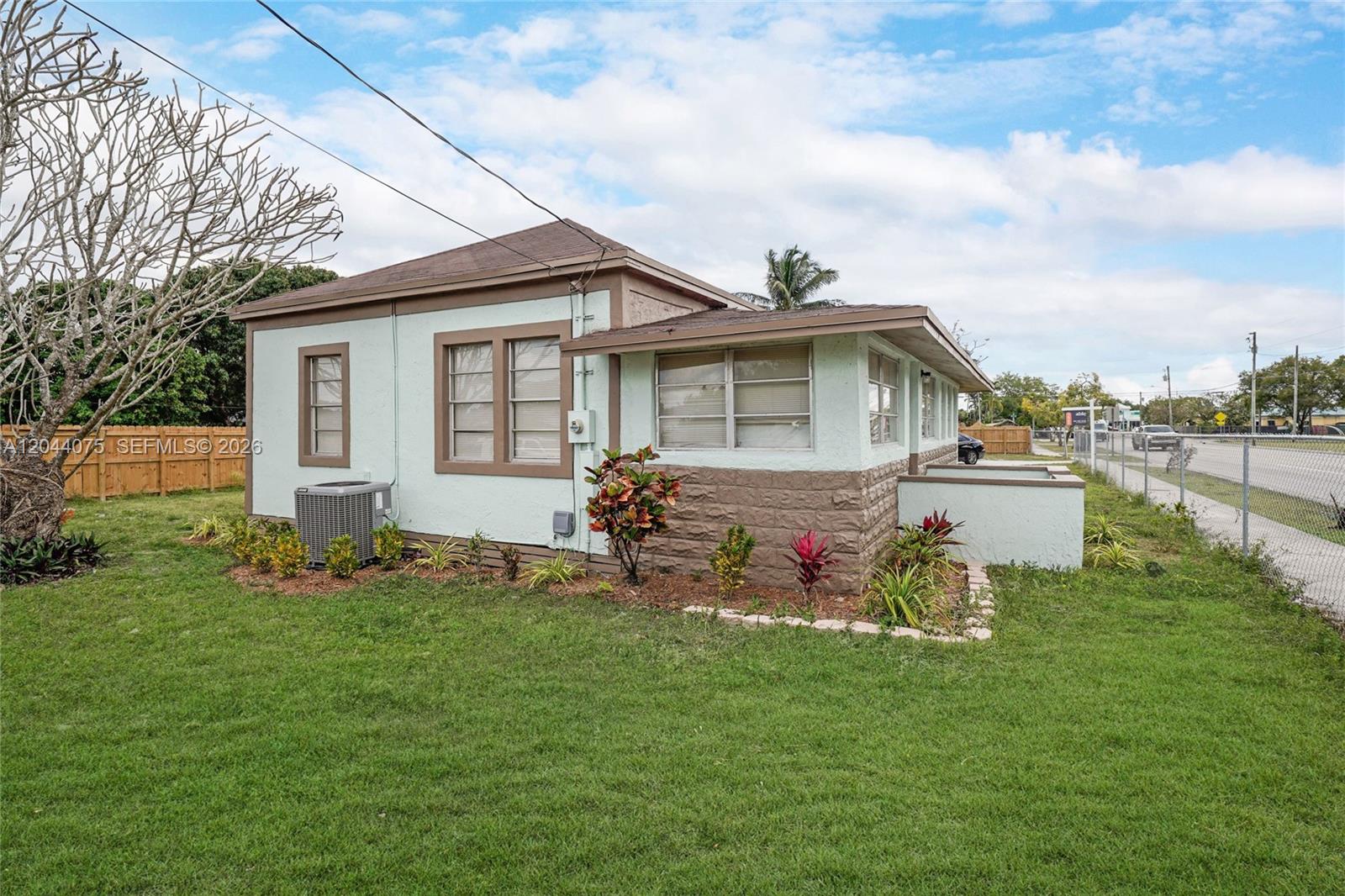 A light green, single-story house with brown trim and a stone-textured base sits on grass — 145 NW 6th Ave, Florida City FL 33034, FLORIDA CITY, FL