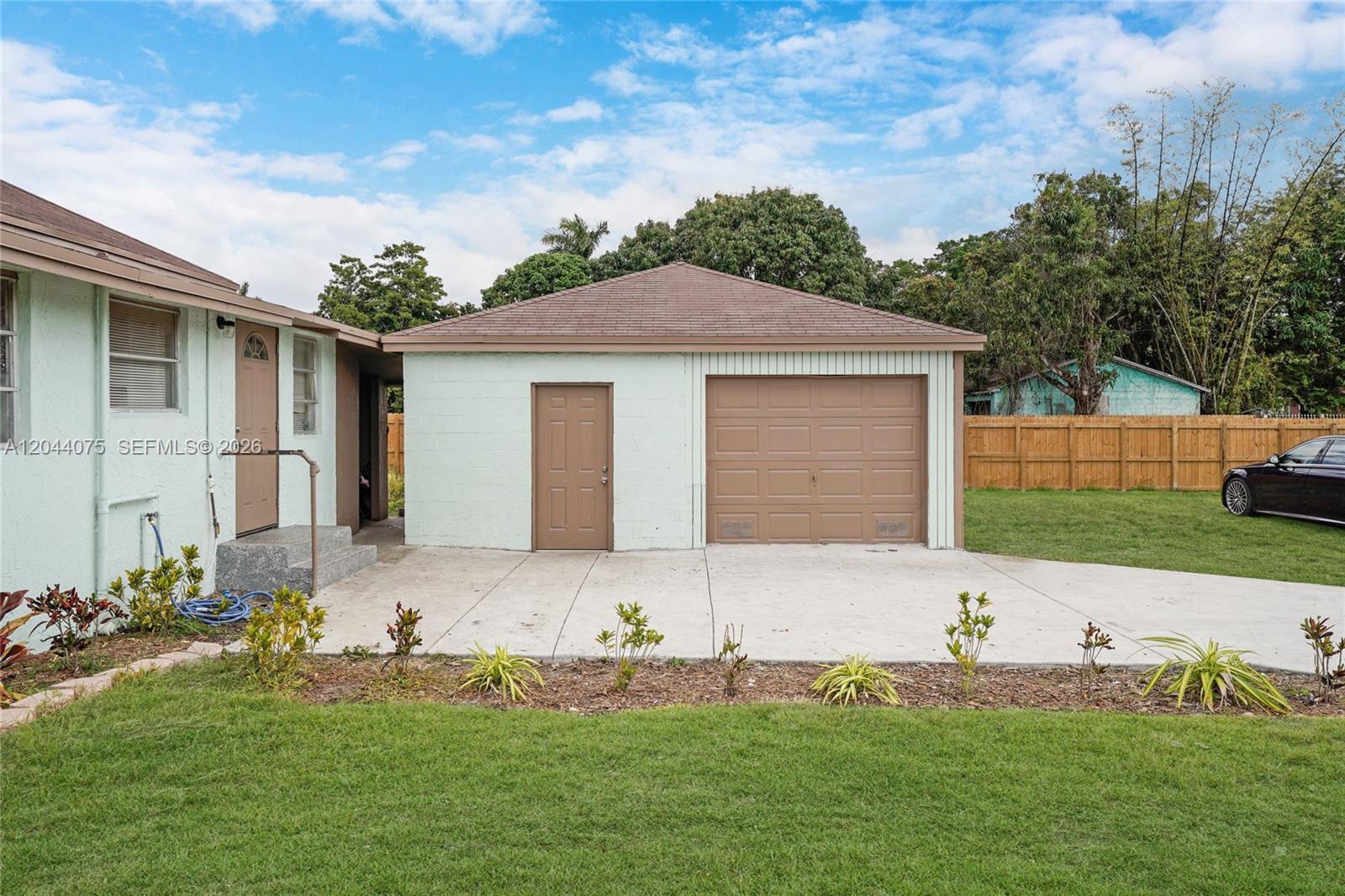 A light green detached garage with a brown door and roof sits on a concrete driveway — 145 NW 6th Ave, Florida City FL 33034, FLORIDA CITY, FL