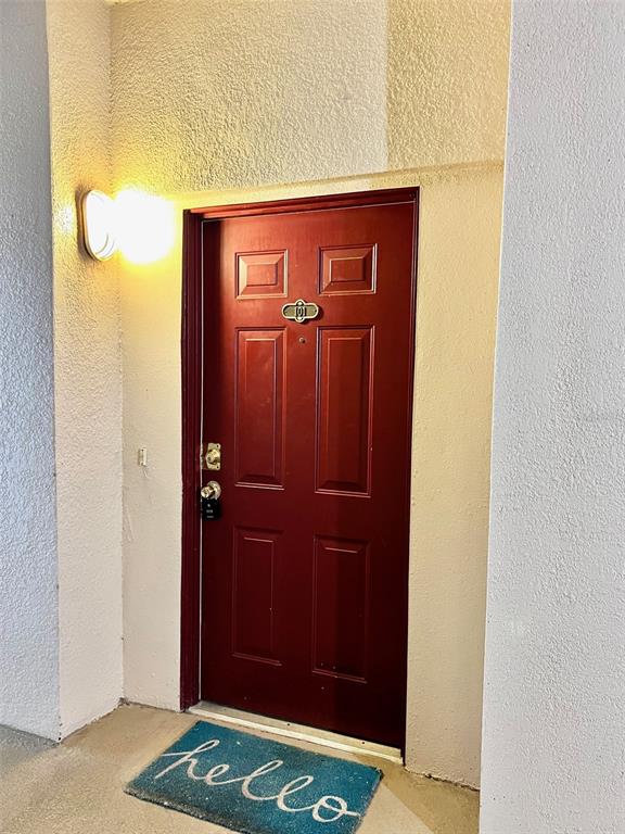 A red front door with a brass number plate and a blue hello doormat — 3000 LAUREL PARK LANE UNIT 101, KISSIMMEE, FL