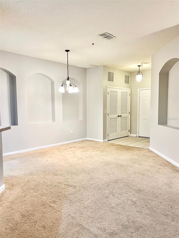 A carpeted dining area features three arched wall niches, a chandelier, and a tiled entryway — 3000 LAUREL PARK LANE UNIT 101, KISSIMMEE, FL