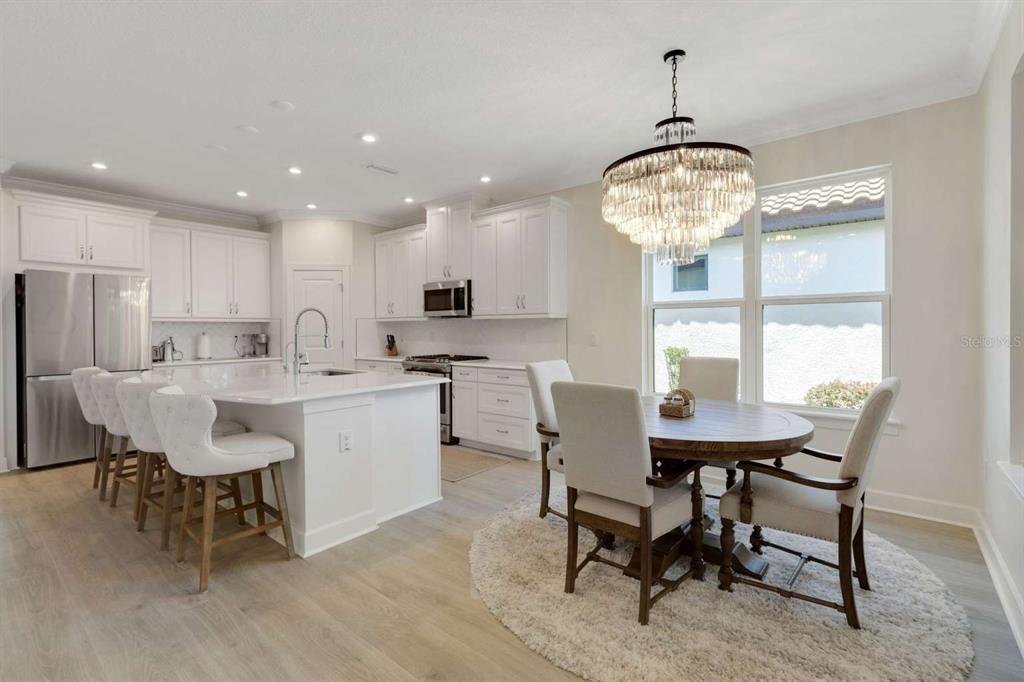 A kitchen and dining area with white cabinets, a large island, and a crystal chandelier — 5410 MOREY FARMS LOOP, PALMETTO, FL