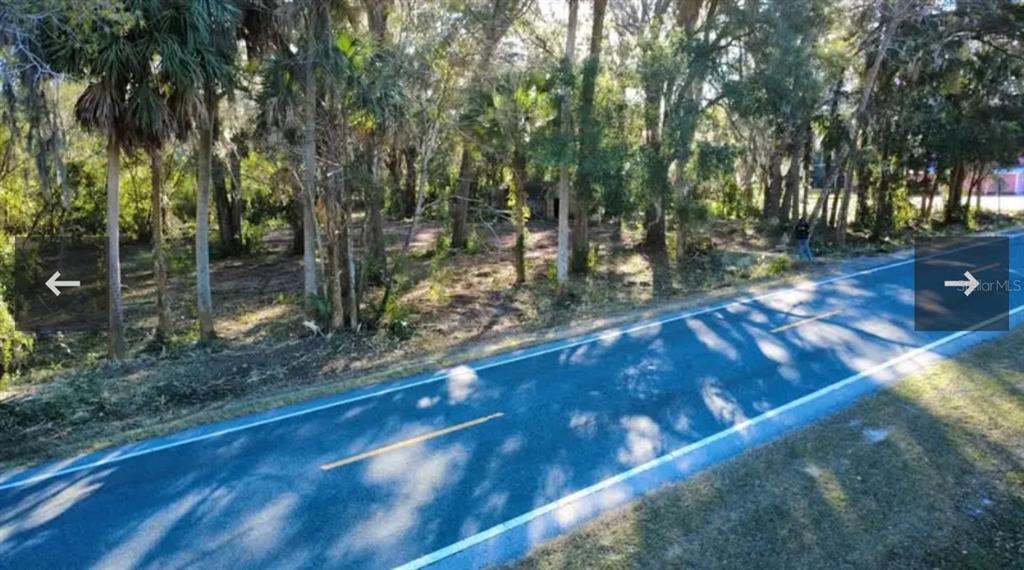 An aerial view shows a wooded, undeveloped lot situated next to a paved two-lane road — 8549 S MAGNOLIA AVENUE, OCALA, FL