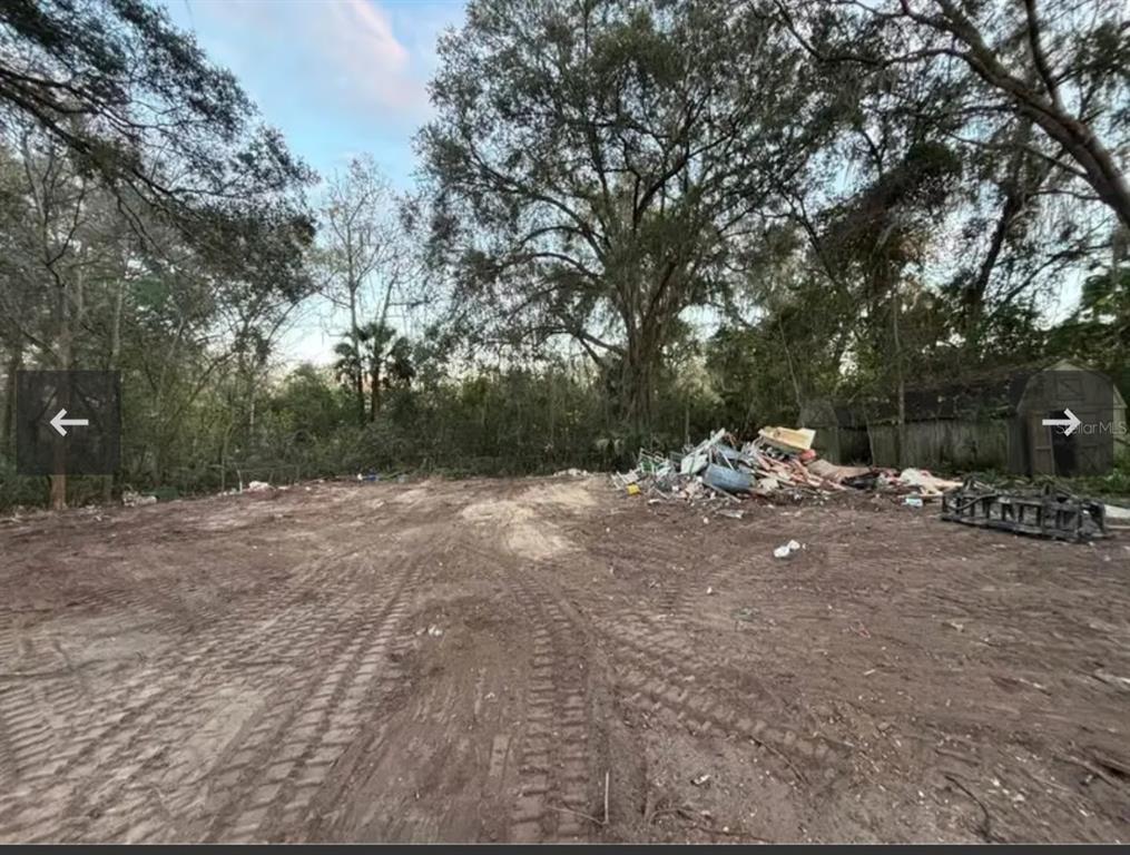 A cleared dirt lot features a pile of debris and a small shed near trees — 8549 S MAGNOLIA AVENUE, OCALA, FL
