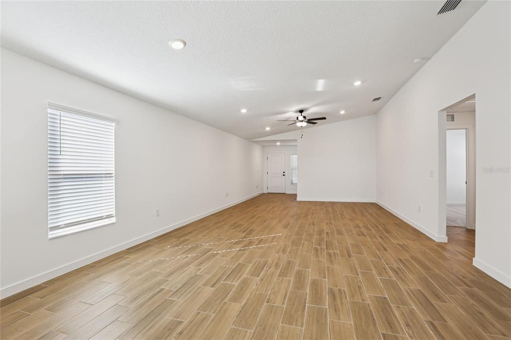 An empty living room features white walls, recessed lighting, a ceiling fan, and wood-look tile — 5283 CAP ROAD, BROOKSVILLE, FL