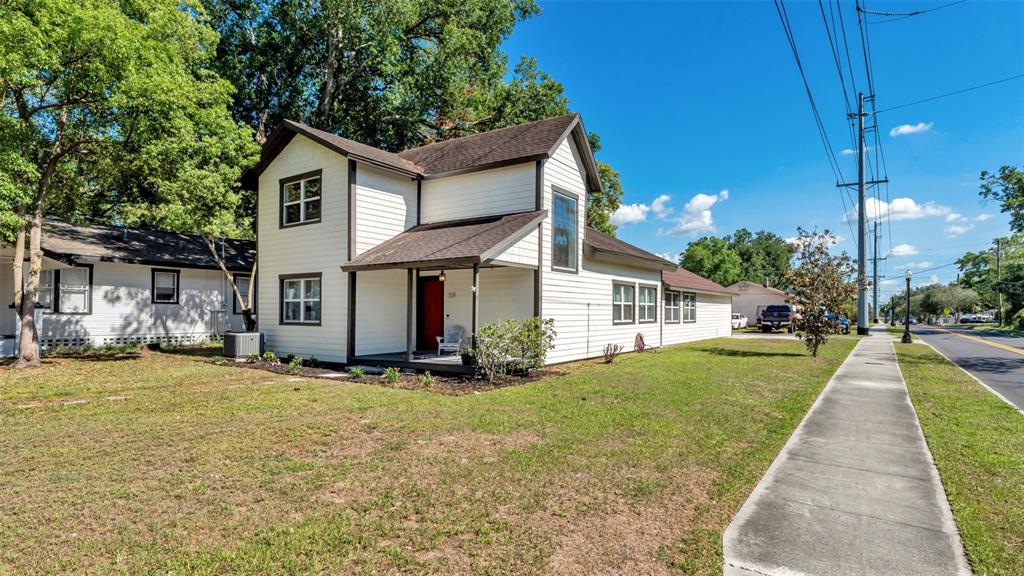 A two-story white house with a covered front porch sits next to a sidewalk — 728 W BELMAR STREET, LAKELAND, FL