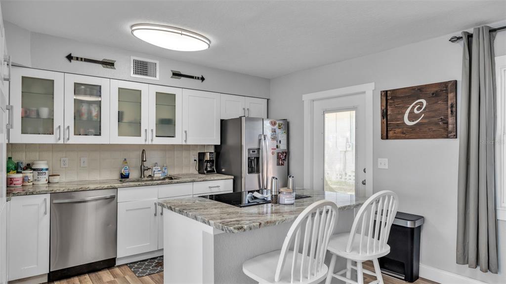 A kitchen with white cabinets, granite countertops, stainless steel appliances, and a small island — 728 W BELMAR STREET, LAKELAND, FL