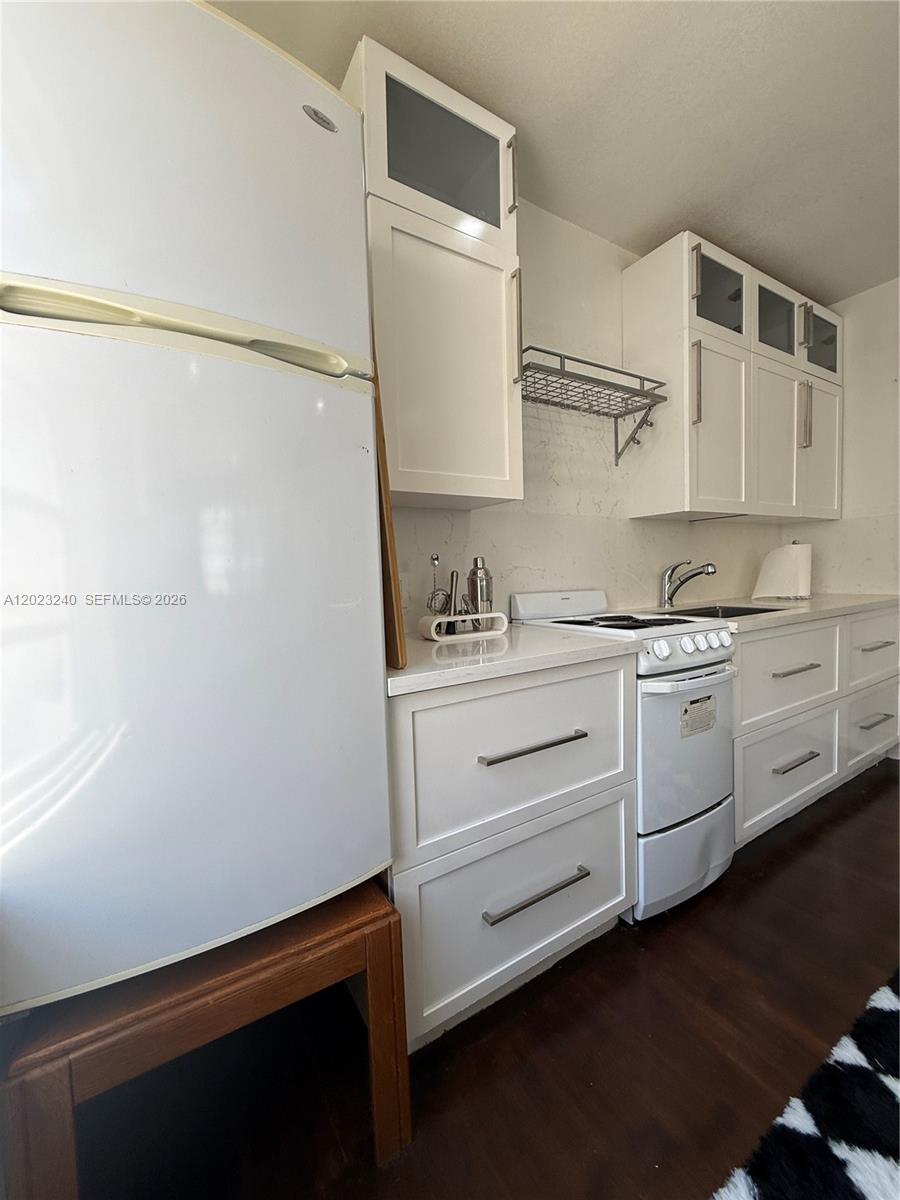 A kitchen features white cabinetry, a white refrigerator, a stove, and dark wood flooring — 723 2nd St # 8, Miami Beach FL 33139, MIAMI BEACH, FL