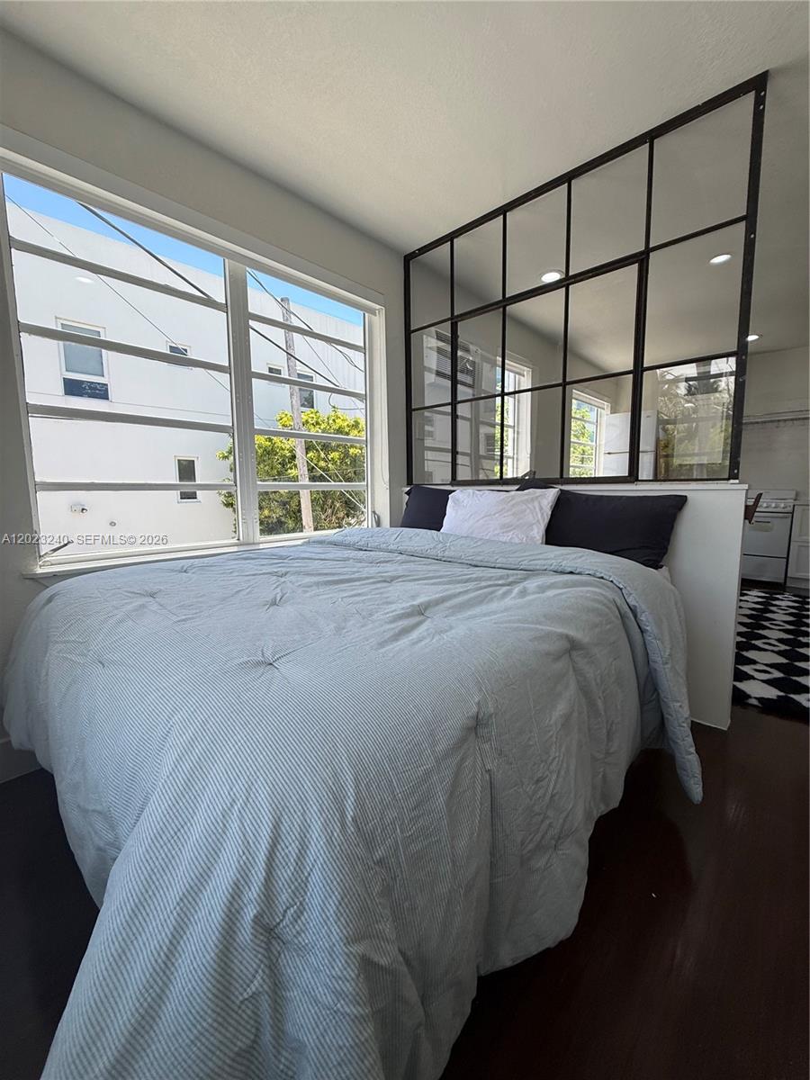 A bedroom features a bed against a black-framed glass partition and large windows — 723 2nd St # 8, Miami Beach FL 33139, MIAMI BEACH, FL