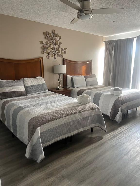 A bedroom features two beds with striped bedding, a ceiling fan, and wood-look flooring — 3100 PARKWAY BOULEVARD UNIT 726, KISSIMMEE, FL