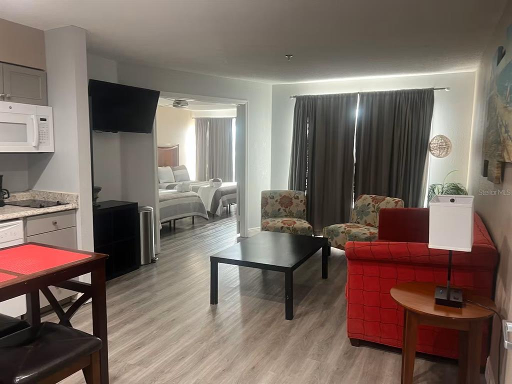 A living room with a red sofa and a dining area opens into a bedroom — 3100 PARKWAY BOULEVARD UNIT 726, KISSIMMEE, FL