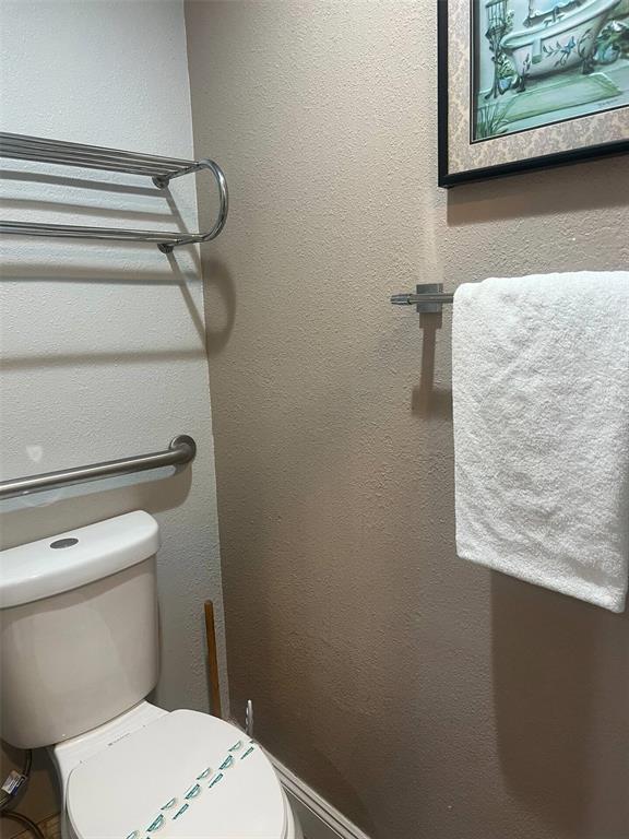 A bathroom features a toilet, a grab bar, a towel rack, and wall-mounted artwork — 3100 PARKWAY BOULEVARD UNIT 726, KISSIMMEE, FL