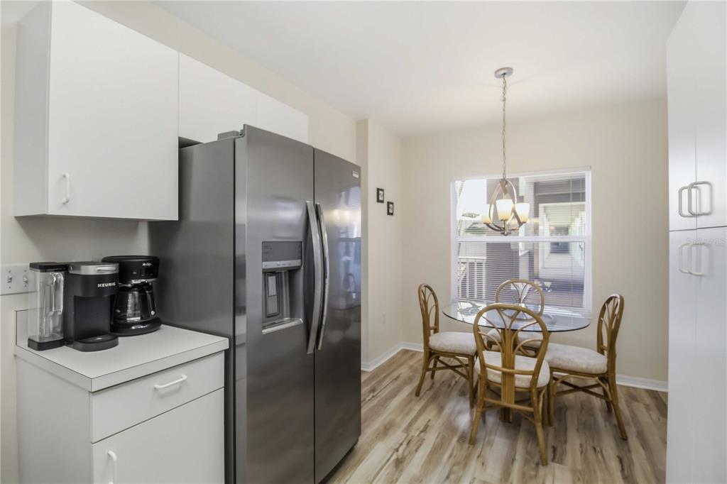 A kitchen features white cabinets, stainless steel appliances, and a dining area with a glass table — 9630 CLUB SOUTH CIRCLE UNIT 6209, SARASOTA, FL