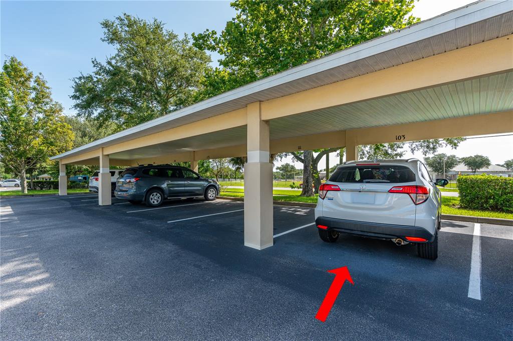 A covered parking area features numbered spaces and two parked SUVs under a roof — 830 AIRPORT ROAD UNIT 103, PORT ORANGE, FL