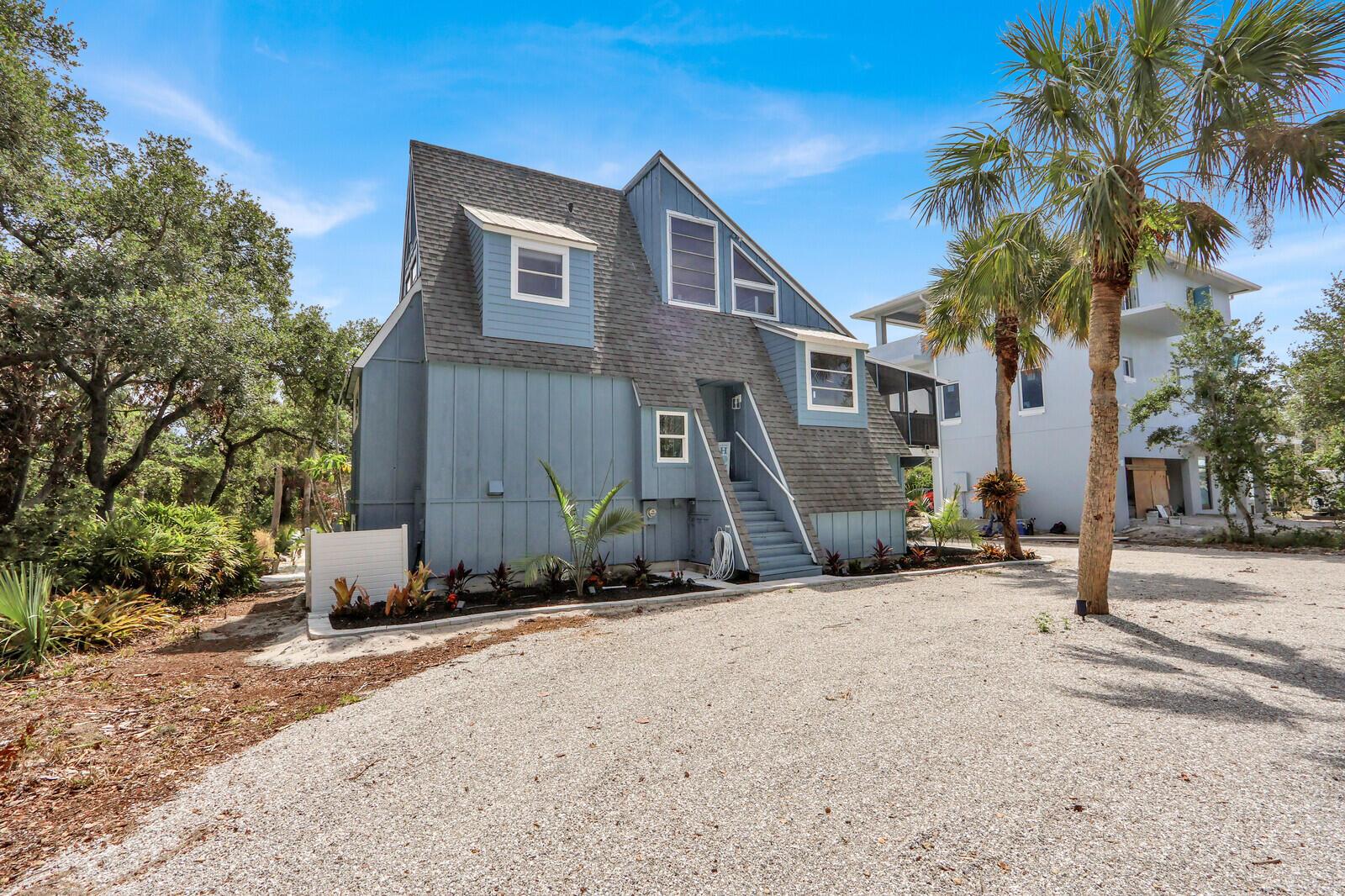A blue, multi-story house with a gravel driveway and a palm tree in the yard — 12000 Conklin Way, Jensen Beach FL 34957, JENSEN BEACH, FL