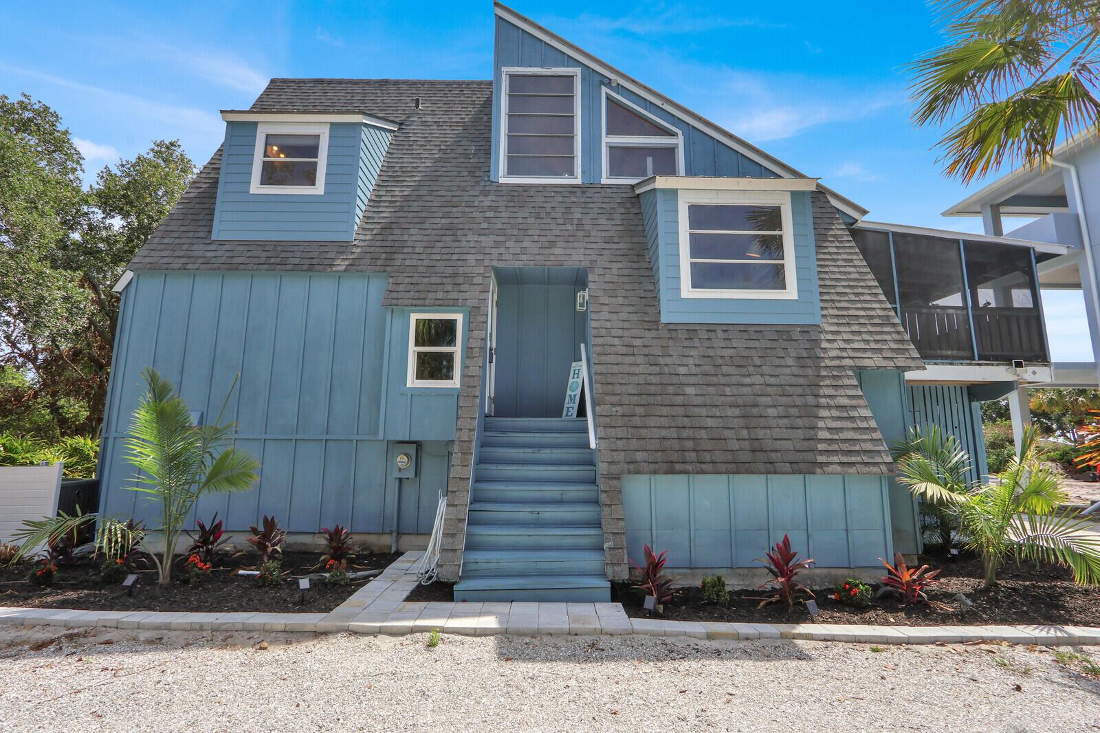 A blue two-story house with a shingled roof, front stairs, and a gravel driveway — 12000 Conklin Way, Jensen Beach FL 34957, JENSEN BEACH, FL