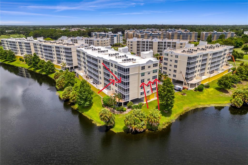 An aerial view shows multi-story apartment buildings situated next to a lake and golf course — 1200 COUNTRY CLUB DRIVE UNIT 1301, LARGO, FL