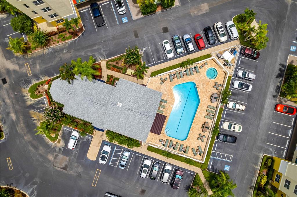 An aerial view shows a multi-story apartment building situated along a waterfront with red arrows — 1200 COUNTRY CLUB DRIVE UNIT 1301, LARGO, FL