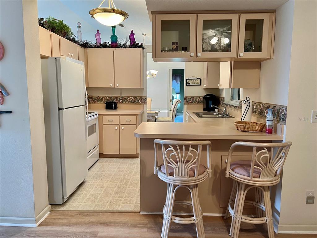 A kitchen features light-colored cabinets, a white refrigerator, a breakfast bar, and two rattan stools — 5333 NW 25TH LOOP, OCALA, FL