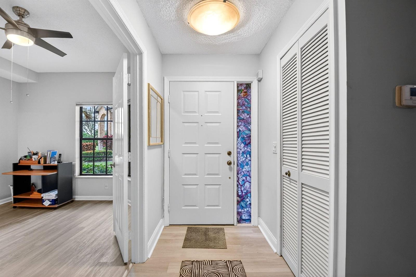 An entryway features a white front door with a stained glass sidelight and louvered closet — 8065 Aberdeen Drive # 101, Boynton Beach FL 33472, BOYNTON BEACH, FL