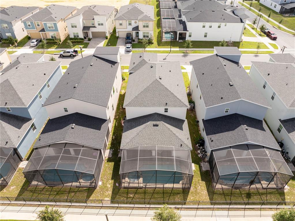 An aerial view shows three suburban houses with screened-in pools in their backyards — 2358 SALTY WINDS WAY, KISSIMMEE, FL