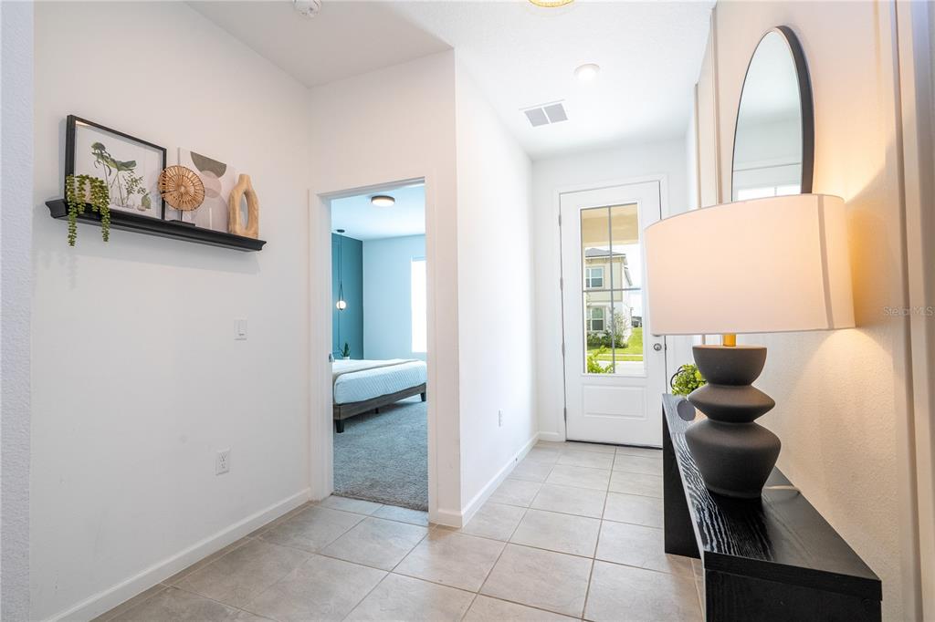 An entryway features tile flooring, a console table with a lamp, and a doorway to a bedroom — 2358 SALTY WINDS WAY, KISSIMMEE, FL