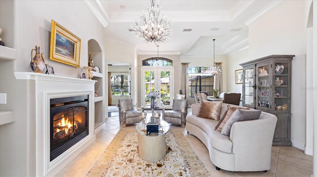 A living room features a fireplace, a curved sofa, two armchairs, and a crystal chandelier — 3754 EAGLE HAMMOCK DRIVE, SARASOTA, FL
