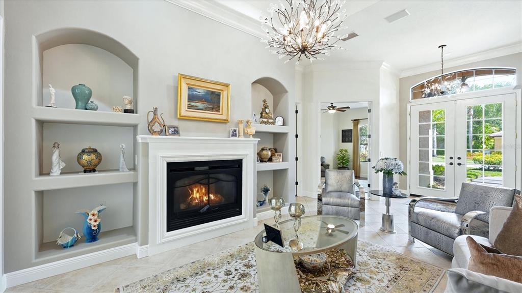 A living room features a fireplace, built-in shelving, tile floors, and glass double doors — 3754 EAGLE HAMMOCK DRIVE, SARASOTA, FL
