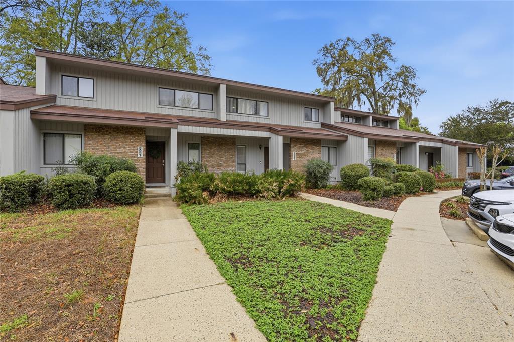A multi-unit residential building features gray siding, brick accents, and concrete walkways — 3939 NW 29TH LANE, GAINESVILLE, FL