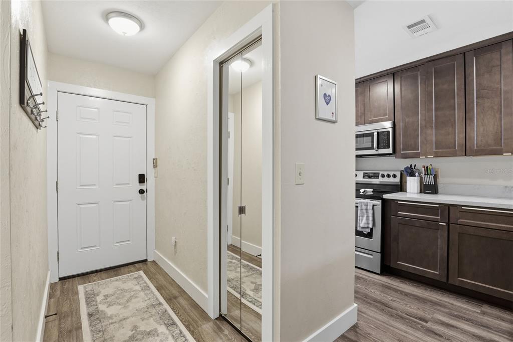 A view of an entryway with a white door, mirrored closet, and adjacent kitchen area — 3939 NW 29TH LANE, GAINESVILLE, FL
