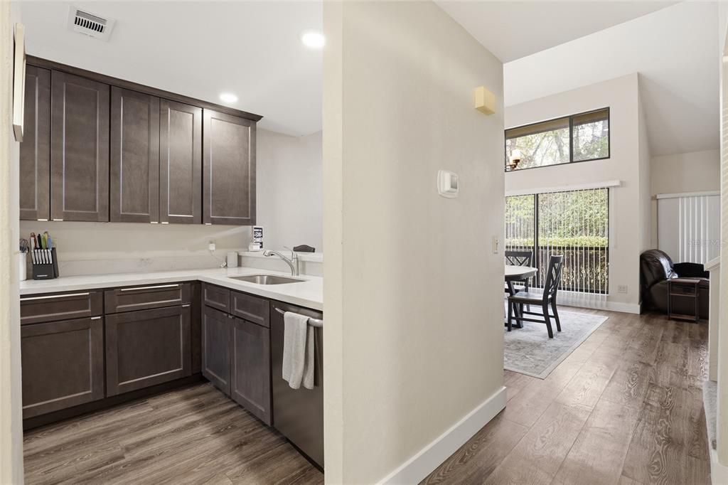A kitchen with dark cabinets and white countertops opens into a dining area and living space — 3939 NW 29TH LANE, GAINESVILLE, FL