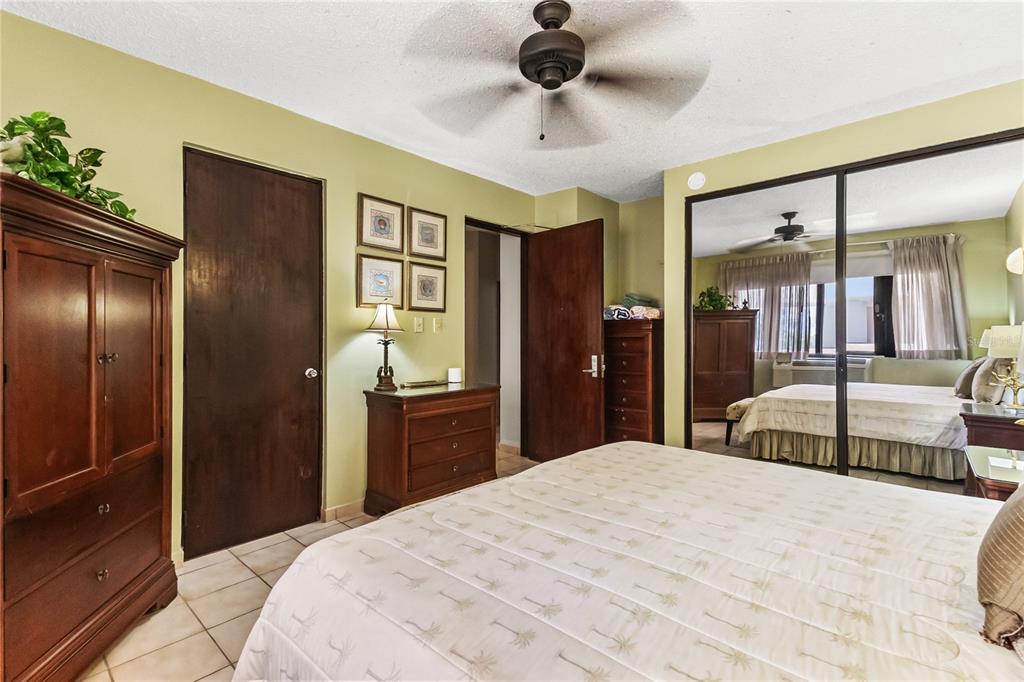 A bedroom with light green walls, tile flooring, a ceiling fan, and mirrored closet doors — 190 CANDELERO DR UNIT 228, HUMACAO, PR