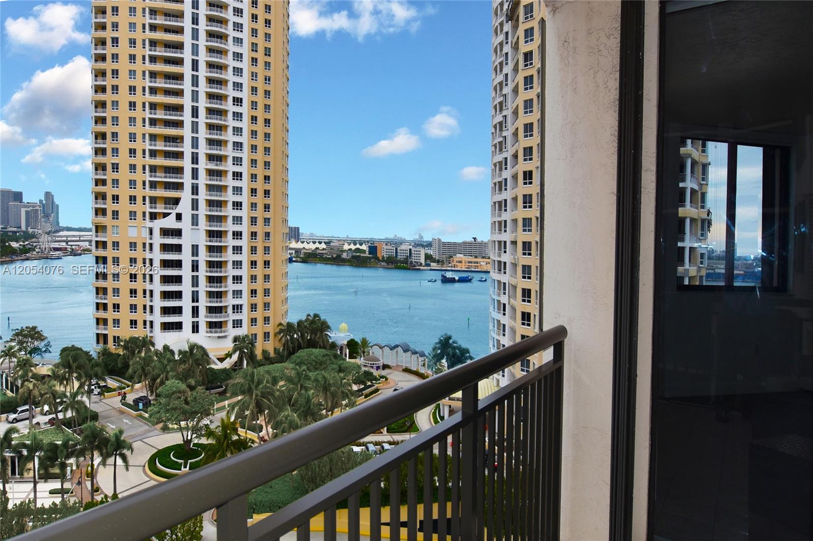 A balcony view overlooks a bay between two tall residential towers and lush landscaping — 540 Brickell Key Dr # 1414, Miami FL 33131, MIAMI, FL