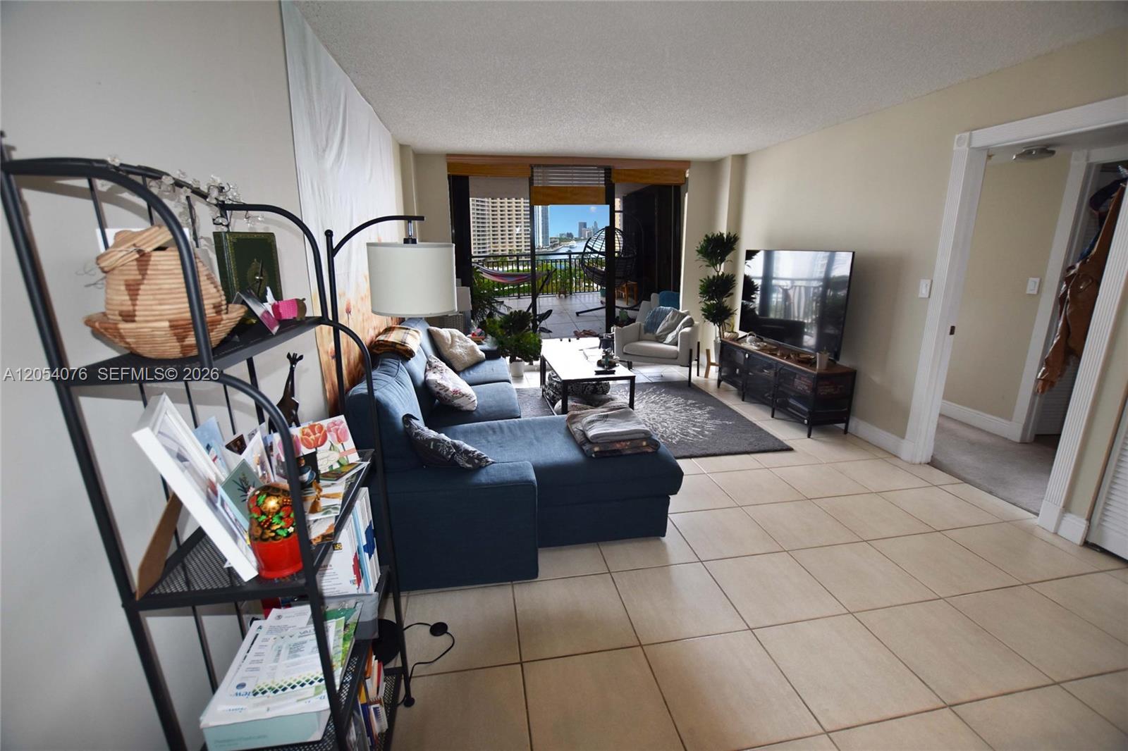 A living room features a blue sectional sofa, tile flooring, and a balcony with city views — 540 Brickell Key Dr # 1414, Miami FL 33131, MIAMI, FL