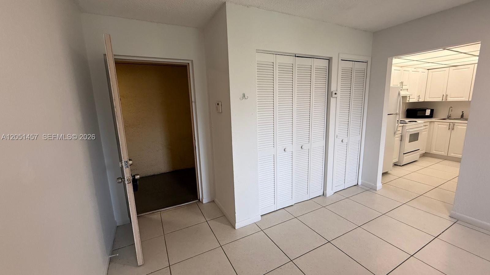 A room with tiled floors, a closet with louvered doors, and an adjacent kitchen — 17530 NW 68th Ave # C3010, Hialeah FL 33015, HIALEAH, FL