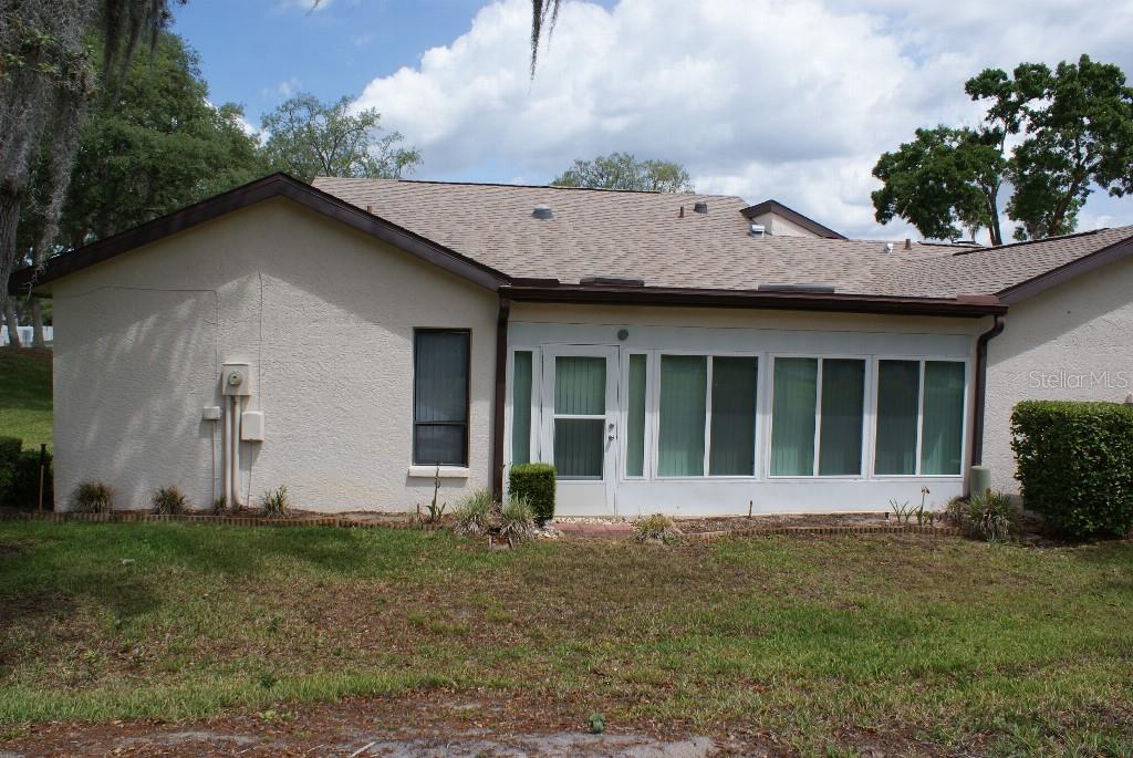 The exterior of a single-story house features a stucco wall and a screened-in porch — 7445 CRESTWOOD DRIVE, WEEKI WACHEE, FL